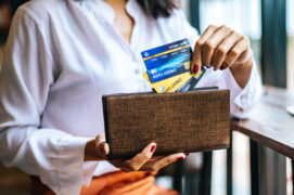 Mulher colocando três cartões dentro de uma carteira (cartão adicional)
