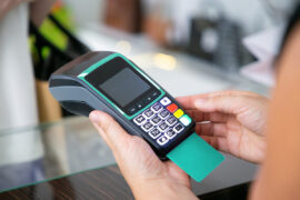 Pessoa digita a senha do cartão em uma maquina de pagamentos.