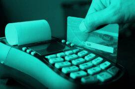 Um cartão de crédito está sendo passado em uma maquininha de pagamento.