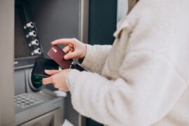 Senha Santander: uma pessoa está em frente a um caixa eletrônico e guarda em sua carteira um cartão de cor escura.