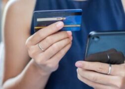 limite do cartão: mulher segurando cartão de crédito e celular