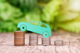 Financiamento de veículo: a miniatura de um automóvel está equilibrada em três pilares de moedas.