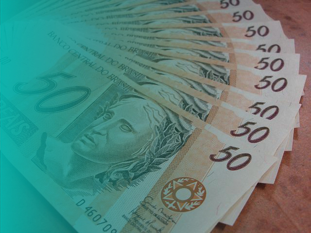 notas de 50 reais espalhadas sob uma mesa (empréstimo consignado do Auxílio Brasil)