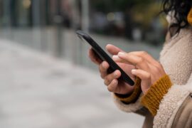 Chave Pix: uma mulher está na rua, mexendo no celular.
