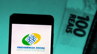 INSS: nota de cem reais e celular ao lado com a tela mostrando o logo da previdência social