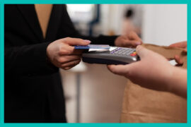 Uma mulher de roupa preta realiza um pagamento por aproximação com o cartão.