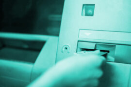 Uma pessoa está inserindo um cartão de crédito no caixa eletrônico.