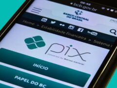 Um celular está na mesa e, em sua tela, é mostrado o site do Banco Central do Brasil e o logo Pix.