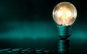 empréstimo na conta de luz: lâmpada em cima de uma pilha de moedas