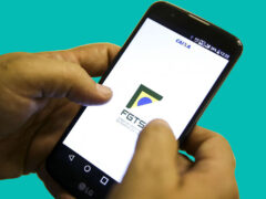 Uma pessoa está mexendo no celular e, na tela, é mostrado o logo do FGTS.