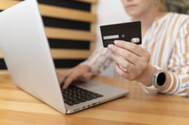 mulher segurando cartão e computador (escolher um cartão de crédito)