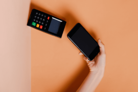 Cartão virtual: uma pessoa está utilizando o celular para efetuar um pagamento por aproximação na maquininha.