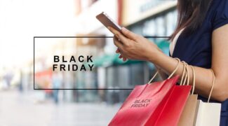 Black Friday: mulher segurando celular e sacolas de compras