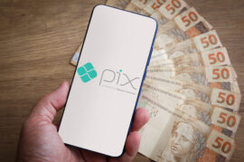 Pix: celular mostrando o logo do pix e notas de cinquenta reais atrás