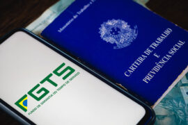Um celular possui o logo do FGTS e, ao lado, está a carteira de trabalho e previdência social.