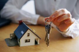 casa em miniatura e mão segurando chaves (financiamento imobiliário)