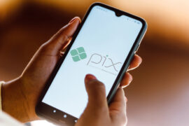Pix Parcelado: uma pessoa está mexendo no celular e, na tela, é mostrado o logo do Pix
