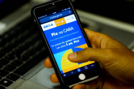 Pix da Caixa: uma pessoa está mexendo no celular e, na tela, é mostrado o site da Caixa Econômica Federal.
