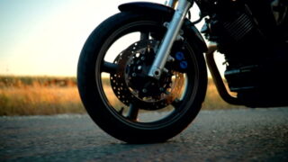 Consórcio de moto: pneu e roda da moto estão em destaque. Ao fundo há uma paisagem.