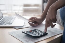 Finanças pessoais: uma pessoa segura um papel enquanto utiliza a calculadora