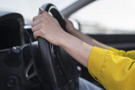 Financiamento de veículo: uma mulher de blusa amarela segura no volante do veículo