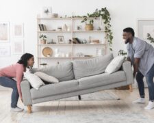 Financiamento para comprar móveis: um homem e uma mulher carregam um sofá de dois lugares.